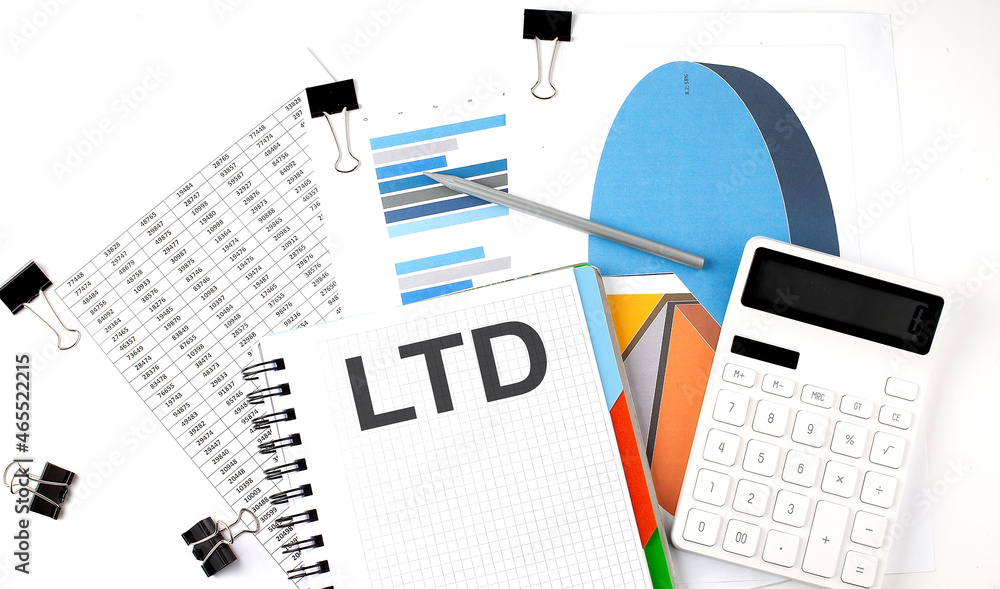 Aufkleber text ltd on a notebook on the diagram and charts with calculator and pen