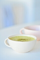Matcha latte on a cafe amde by a barista, a light pink cup on the background, Matcha green tea latte in a cup. Top view. Copy space. Green tea matcha latte is delicious to enjoy and get energy from