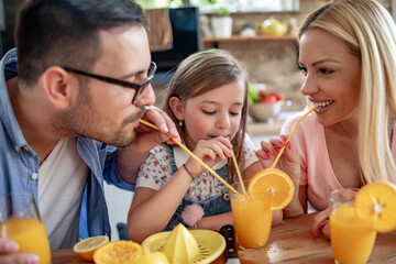 Happy family in the kitchen making orange juice