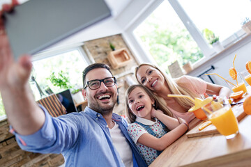 Family making orange juice and taking selfie in the kitchen