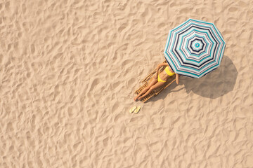 Fototapeta na wymiar Woman resting in sunbed under striped beach umbrella at sandy coast, aerial view. Space for text