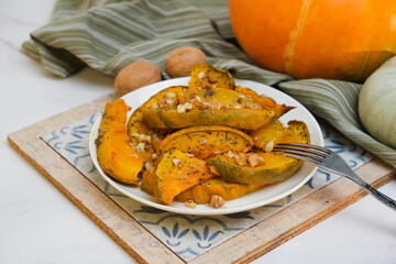 Plate of baked pumpkin with provencal herbs and walnuts. Seasonal healthy vegetarian autumn Thanksgiving meal.