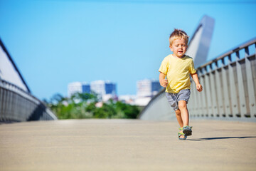 Cute blond toddler boy run on a path walk in park