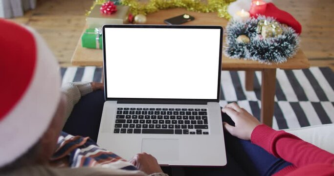 African american mother with daughter making laptop christmas video call, with copy space on screen