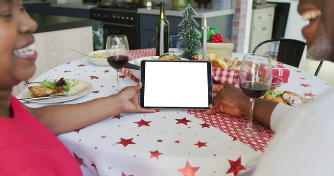 Smiling african american couple making tablet christmas video call, copy space on screen