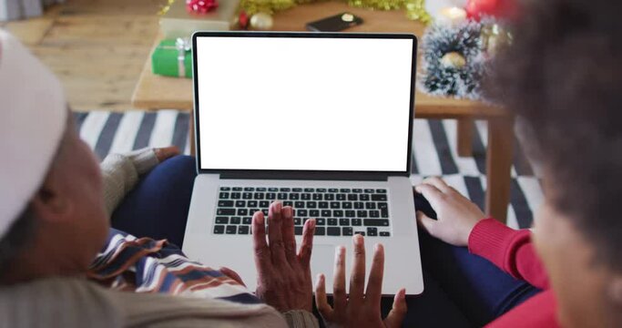 African american mother with daughter making laptop christmas video call, copy space on screen