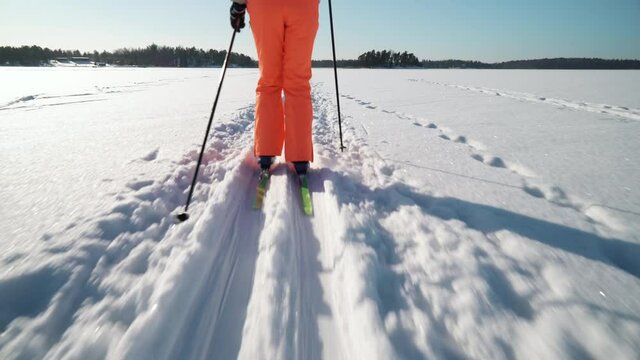 A woman going cross-country skiing on a frozen bay in Finland on a frosty sunny day. Steadicam Tracking Shot.