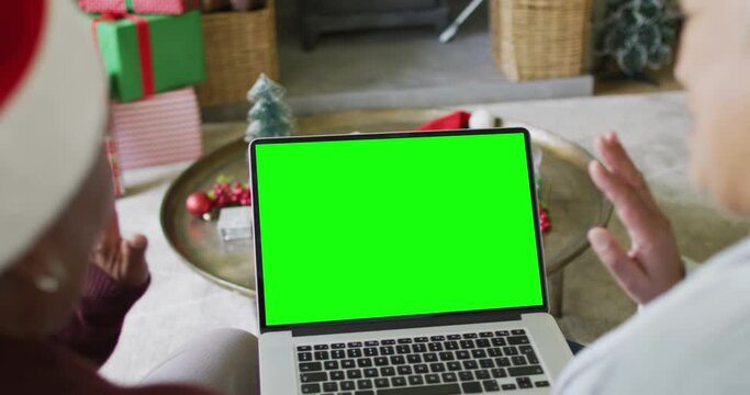 Senior diverse couple in santa hats making laptop christmas video call, with green screen