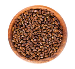Cassia tora beans in wooden bowl, isolated on white background. Sicklepod or Senna obtusifolia. Clipping path. Top view.