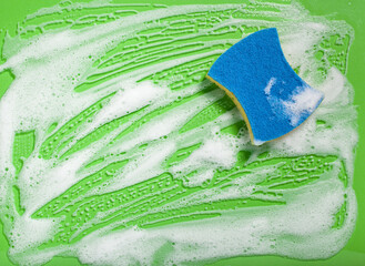 cleaning sponge wiping foam soap suds on green background, household washing concept - obrazy, fototapety, plakaty