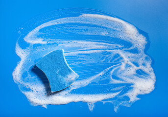 cleaning sponge wiping foam soap suds on blue background, household washing concept