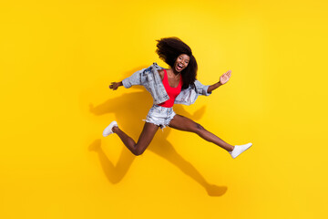 Naklejka na ściany i meble Full length body size photo of girl jumping laughing running cheerful isolated vibrant yellow color background