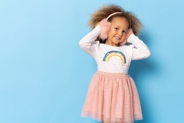 Cute little girl wearing stylish earmuffs isolated over blue background