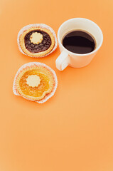 delicious apricot and cherry jam pastry in a paper backing cup and coffee cup on orange background