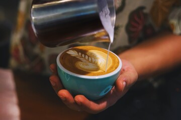 Close up barista hands making coffee latte art,Barista pouring milk in coffee mug for making latte art at cafe’