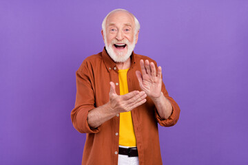 Photo of impressed elder man clap arms wearing brown shirt isolated over purple color background