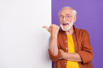 Photo of funny old man indicate empty space wearing eyewear brown shirt isolated over purple color background - obrazy, fototapety, plakaty