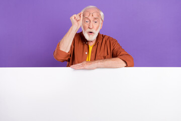 Photo of impressed aged man look wall wearing eyewear brown shirt isolated over purple color background