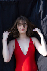 Fototapeta premium Young caucasian woman in red swimsuit near black cloth