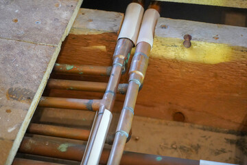 Close up of copper pipes under floor boards