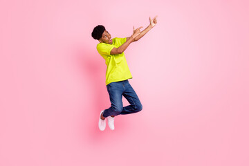 Fototapeta na wymiar Full size photo of afro american young man point finger empty space jump isolated on pink color background
