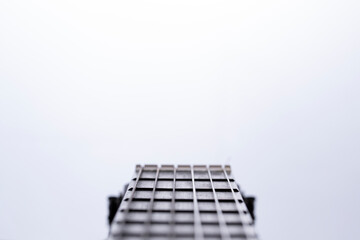 A close-up of frets and strings on the neck of a classical acoustic guitar against a white...
