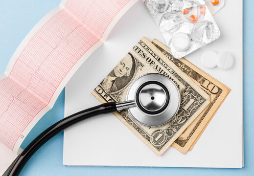 Cost of health care with USD bank notes, stethoscope, cardiogram and medicaments. Price of medicine. Medical expenses. Dollar cash money. Cost of medicinal products and treatment concept. Top view