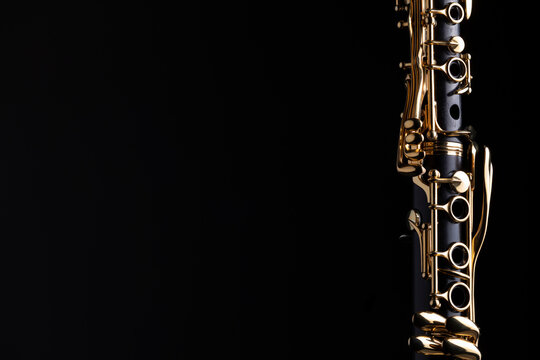Part of a clarinet with gold plated keys on a black background. A woodwind instrument common to classical music.
