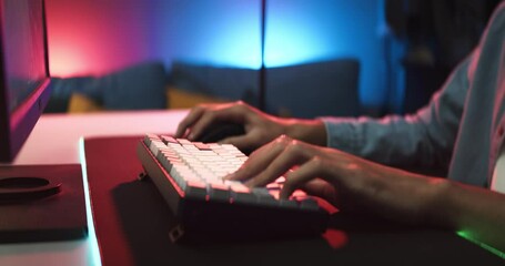 Young Asian man playing online computer video game, colorful lighting broadcast streaming live at home. Ecstatic celebration winning a match. Gamer lifestyle, E-Sport online gaming technology concept