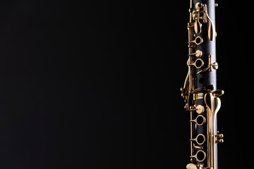 Part of a clarinet with gold plated keys on a black background. A woodwind instrument common to...