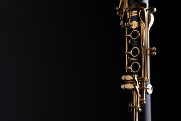 Part of a clarinet with gold plated keys on a black background. A woodwind instrument common to classical music. - obrazy, fototapety, plakaty