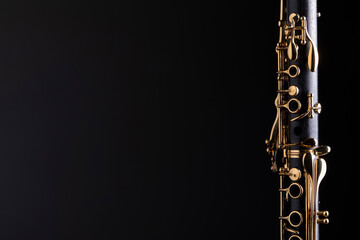 Part of a clarinet with gold plated keys on a black background. A woodwind instrument common to classical music.