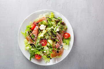 Overhead view of prosciutto slice salad on white plate