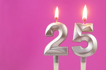 Silver birthday candles on pink background with copy space for text, number 25