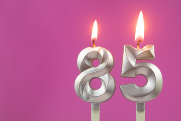 Silver birthday candles on pink background with copy space for text, number 85
