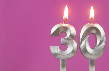 Silver birthday candles on pink background with copy space for text, number 30