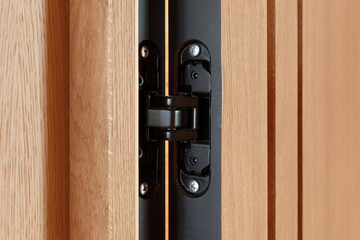 A powerful modern door hinge cut into a heavy wood door.