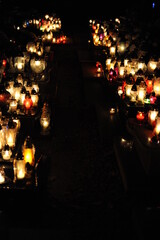 Candle lights on graves and tombstones in cemetery at night in Poland on All Saints’ Day or All Souls’ Day or Halloween or Zaduszki or Day of the Dead