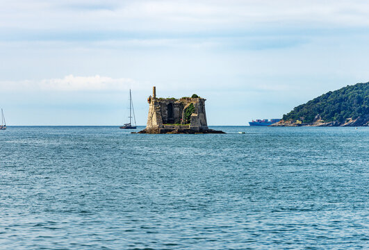 Ancient Scola Tower (Torre Scola) or of Saint John Baptist, XVII century, entrance the port of the Gulf of La Spezia, Porto Venere, Liguria, Italy, Europe. On the right the island of Palmaria.