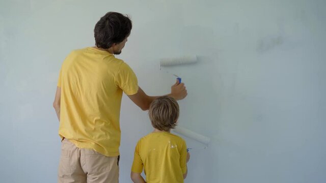 A young man and his son are doing a walls renovation in their home. They are painting the wall using paint rollers. Make renovation yourself. Teaching children how to do repairs by your own