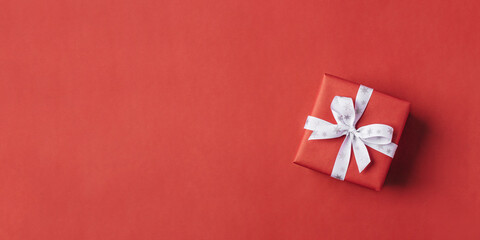 Gift boxe with white bow on a red backdrop.