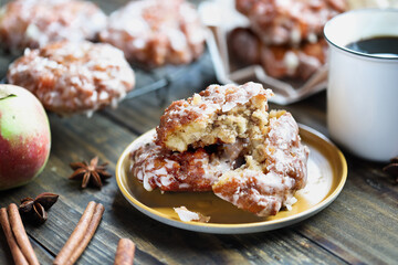 Glazed apple fritters and hot coffee with fresh apples, cinnamon bark and anise. Selective focus with blurred background and foreground. 