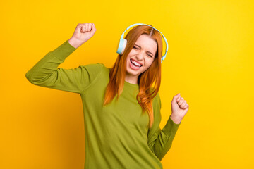 Photo portrait red haired woman dancing listening music in earphones isolated vivid yellow color...
