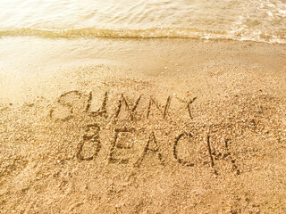 The inscription Sunny beach on the sea sand