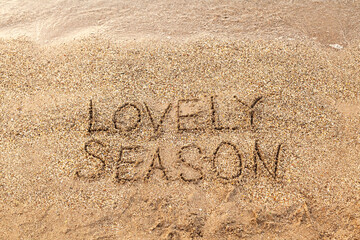 Lovely Season lettering on the sea sand