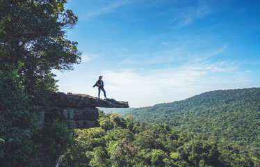 Woman standing on a rock with camera in the mountain.