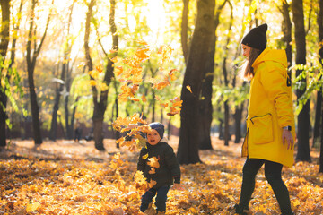 boy in autumn leaves playing with mom