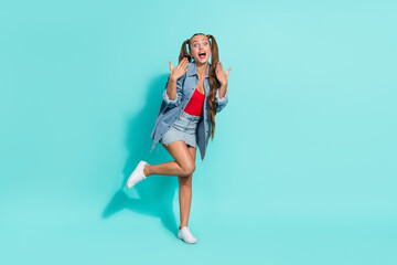 Photo of attractive impressed young woman dressed denim jacket screaming rising hands smiling walking isolated teal color background