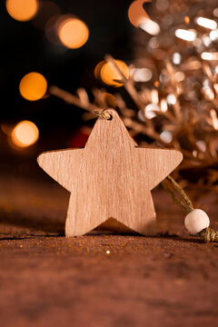 Festive New Year card with free space for text. Wooden star and Christmas decorations on a dark background with beautiful bokeh vertical photo