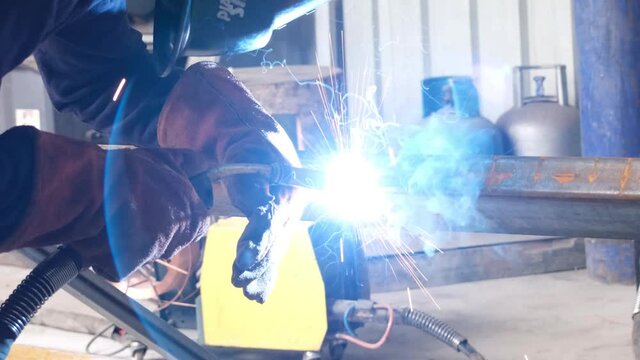 welding close up, worker welds metal profile pipe in workshop
